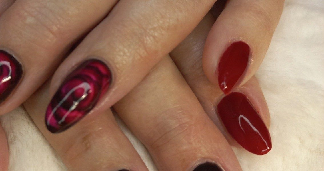 Nagels met donkerrode rozen naast effen rode nagels