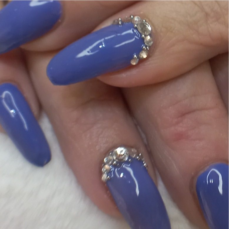 Close-up van een blauwe nagel met een rij steentjes